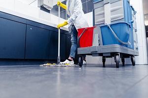 Low shot of cleaning lady mopping the floor in restroom | commercial maintenance