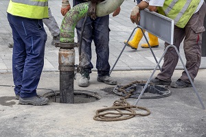men putting a pipe in a manhole | commercial plumbing services